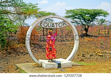 QUEEN ELIZABETH NP, UGANDA - AUGUST 10: African woman at the equator marking on August 10, 2004 in  Queen Elizabeth National Park. Sign of crossing Equator.