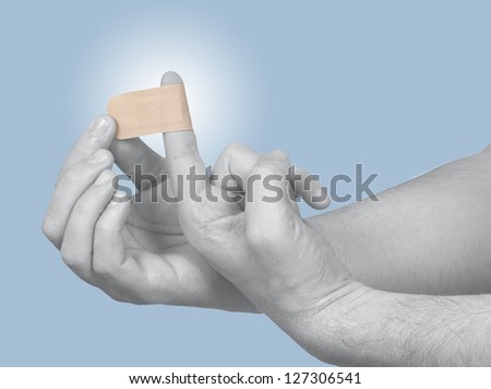 Hand putting Adhesive Bandage on finger. Concept photo with Color Enhanced skin with read spot indicating location of the pain.