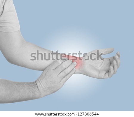 Acute pain in a man wrist. Male holding hand to spot of wrist pain. Concept photo with Color Enhanced blue skin with read spot indicating location of the pain.