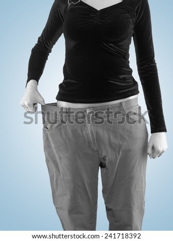 Woman shows her weight loss by wearing an old big trousers. Weight loss concept.