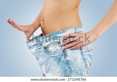Beautiful young woman with big jeans, isolated on white.Woman showing how much weight she lost. Healthy lifestyles concept.