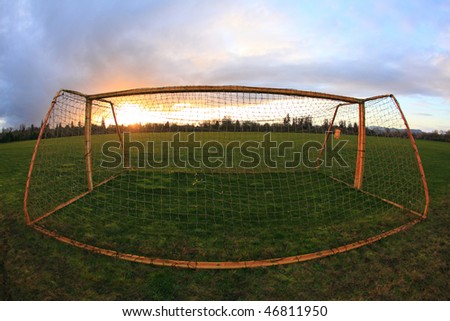 Unusual perspective of an old soccer goal in the park at sunset.