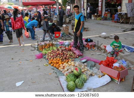 LAOMENG - DECEMBER 16: Fruit trader waits for customers at a market in Lao Meng, China on December 16, 2012. People from 13 tribes/ethnic groups from China and Laos congregate here to trade daily.