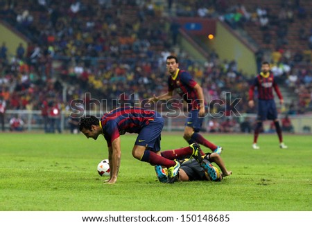 KUALA LUMPUR - AUGUST 10: FC Barcelona\'s Cesc Fabregas (maroon/blue) dribbles past Malaysia\'s defender (fallen) in a game at the Shah Alam Stadium on August 10, 2013 in Malaysia. Barcelona wins 3-1.