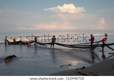 PADANG - AUGUST 25: Fishermen work as a team pull in the fishing nets from the sea in Padang, West Sumatera, Indonesia on August 25, 2013. Resources from the sea is a major revenue earner.