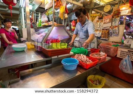 SINGAPORE - SEPTEMBER 19: A man attends to a customer at a chicken meat stall on September 19, 2013 in Toa Payoh Market, Singapore. The traditional Asian wet market still exist in this modern city.