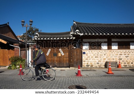 JEONJU, SOUTH KOREA - 03 NOVEMBER 2014: An unidentified cyclist cycles past old traditional Korean houses in this vintage town. The Korean Hanok Village in Jeonju is a major tourist attraction.