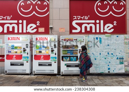 OSAKA, JAPAN - 30 NOVEMBER 2014: A young girl checks out the beverage vending machines in Osaka city. Unmanned vending machines selling snacks, cigarettes and beverages are common in Japan.