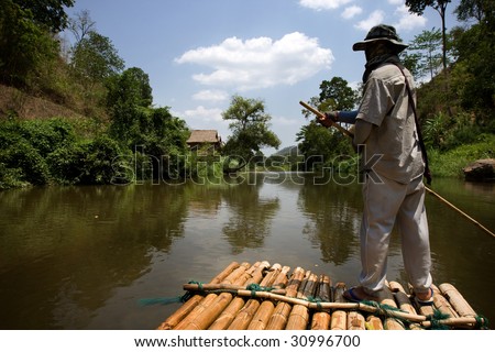CHIANG MAI, THAILAND - APRIL 23: A bamboo raft and his handler negotiates the meandering river downstream. April 23, 2009 in Thailand.