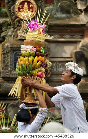 BALI - JANUARY 14: Village woman loads the offering of food basket on her head in a procession to the village temple January 14, 2010 in Bali, Indonesia.