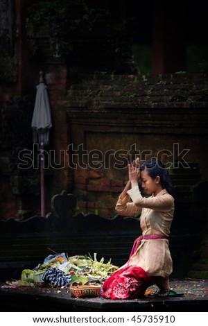 BALI - JANUARY 15: Balinese lady kneels down to pray at the Pura Tirta Empul, Tapaksiring January 15, 2010 in Bali, Indonesia.