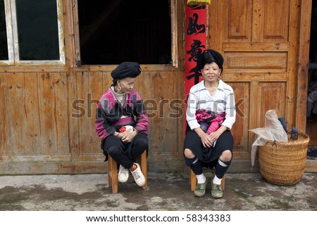 LONGJI, CHINA - MAY 21: Yao ethnic minority women work as porters, waiting for tourist outside their cottage home. May 21, 2010 in Longji, China.