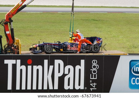 KUALA LUMPUR - APRIL 2: Track marshals lift Red Bull\'s Mark Webber\'s car onto a transporter on practice day at the 2010 Petronas Malaysia F1 Grand-Prix on April 2, 2010 in Sepang, Malaysia.