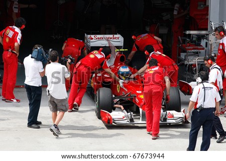 KUALA LUMPUR - APRIL 2: Ferrari\'s mechanics push Fernando Alonso\'s car back into the garage on practice day at the 2010 Petronas Malaysia F1 Grand-Prix on April 2, 2010 in Sepang, Malaysia.