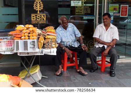 KUALA LUMPUR - MAY 22: An Indian trader sells snack food on May 22, 2011 in Kuala Lumpur, Malaysia. The snack food includes roasted peanuts, beans and a deep fried spiced flour strips known as muruku.