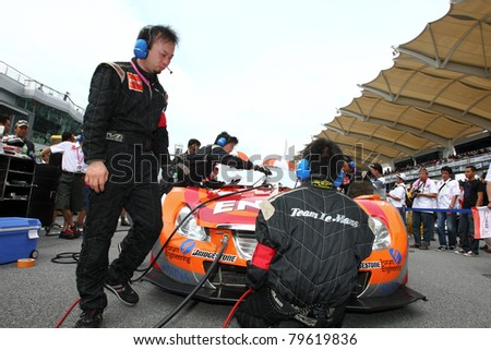 SEPANG - JUNE 19: The Lexus Team LeMans Eneos\' mechanics work on the car at the start grid of Sepang International Circuit during the Japan SUPER GT Round 3 race on June 19, 2011 in Sepang, Malaysia.