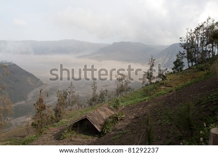 JAVA, INDONESIA - JULY 1: House and farm overlooking Mount Bromo spewing out ash and smoke on July 1, 2011 in Java, Indonesia. Indonesia sits on the \'ring of fire\' with many active volcanoes.