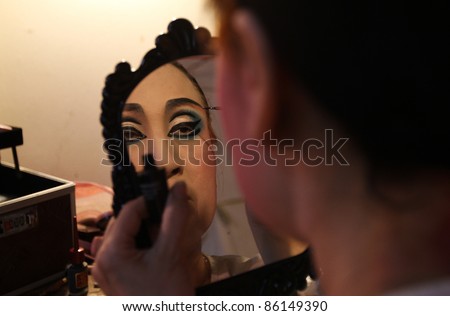 AMPANG, MALAYSIA – OCT 05: A Chinese Opera actress applies makeup backstage before her show at the Lam Thian Kiong Temple celebrating the ‘Nine Emperor Gods’ Festival on October 05, 2011 in Ampang, Malaysia.