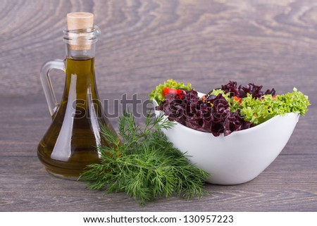 Fresh salad and oil on wooden background