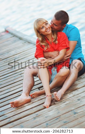 The happy young couple walking on a wooden pier on the seashore and are dressed in fashionable clothes. Having fun.