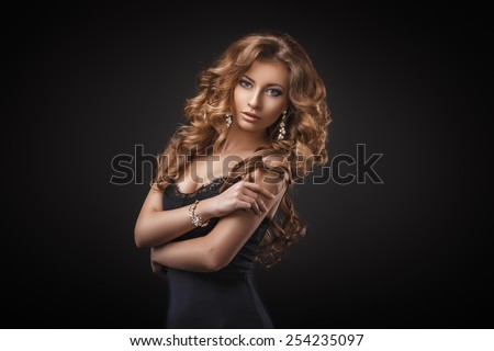 Portrait of wonderful young blonde woman with long hair looking at camera. Sexy girl in blue dress. Jewelry. Hairstyle. Glamour makeup. Vogue. Curly hair.
