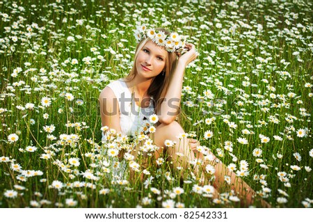 Beautiful young girl with diadem on chamomile field