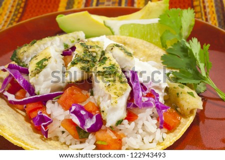 A close-up photo of a small fish taco plate with lime and avocado.