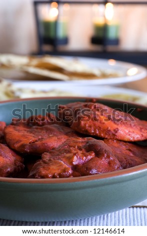 Tandoori Chicken - Indian food. Papadum, naan and candles in background.