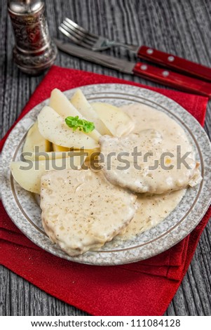 Meat with white sauce and potatoes on a side