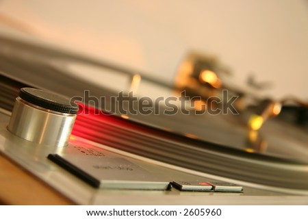 Red strobe light on a silver DJ turntable, with spinning white label record, platter and light