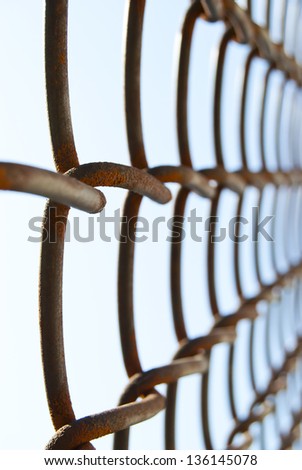 Fragment of an old fence of metal mesh with areas of loose rust.