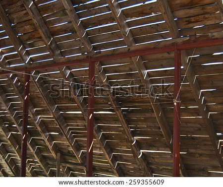 Open attic roof with gaps between the planks of wooden crates and metal resistant racks.