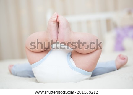 baby bottom with feet in the air sitting on the bed