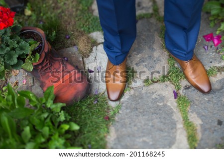 groom shoes close up near a dwarf shoe  filled with geranium