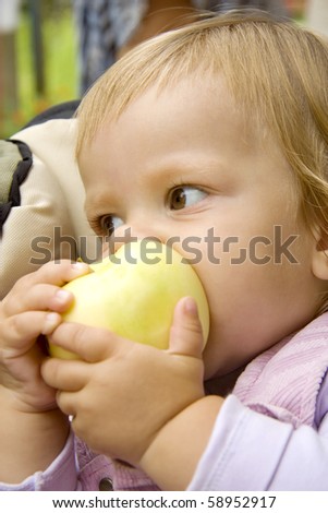 small child bites the big apple and holds its two hands