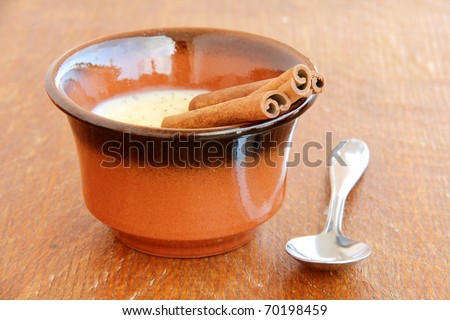 rice pudding in clay cup on wooden background .Creamy rice pudding with cinnamon. A simple, nutritious dessert made from rice, milk, eggs, vanilla and sugar.
