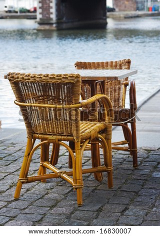 wicker chairs of an open-air cafe installed on cobblestone pavement