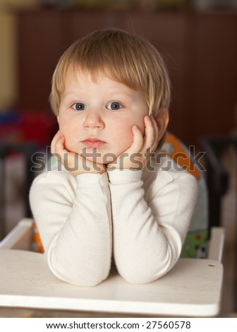 thoughtful blond boy resting elbows on the table