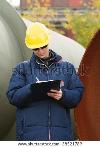Woman in yellow hard hat taking notes while standing in a construction site