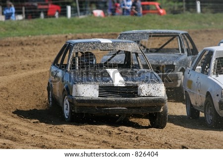 Saloon stock cars racing on a flat dirt track.  At a small speedway track in New Zealand.
