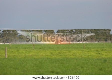 Large Irrigator on a flat land Dairy farm in Canterbury, New Zealand with Rainbow colors showing in mist.