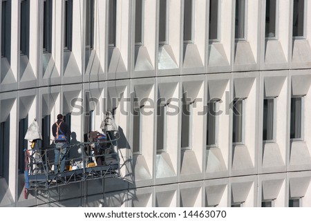 Two building maintenance staff working on a modern multi story building