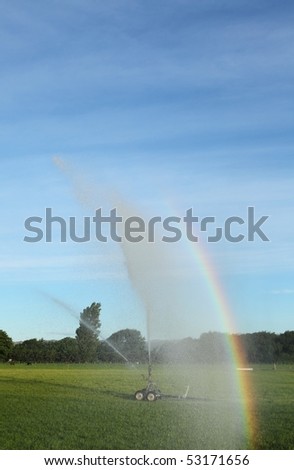Irrigation system operating in the late afternoon, with a cool rainbow showing in the spray.