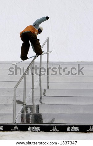 A snowboarder doing a hand rail.