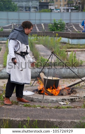 KALININGRAD, RUSSIA - JUNE 17: man in suit of Teutonic knight cooks food on knightly tournament \