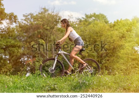 happy slim girl biking in summer park