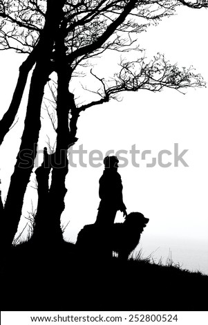 woman and dog silhouettes under trees, monochrome