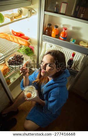 woman eating dessert near refrigerator