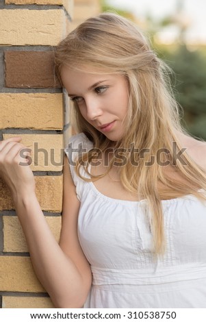 attractive sad blond young woman near bricks wall