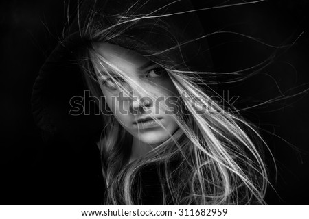 scared girl in black hood looking back in dark monochrome